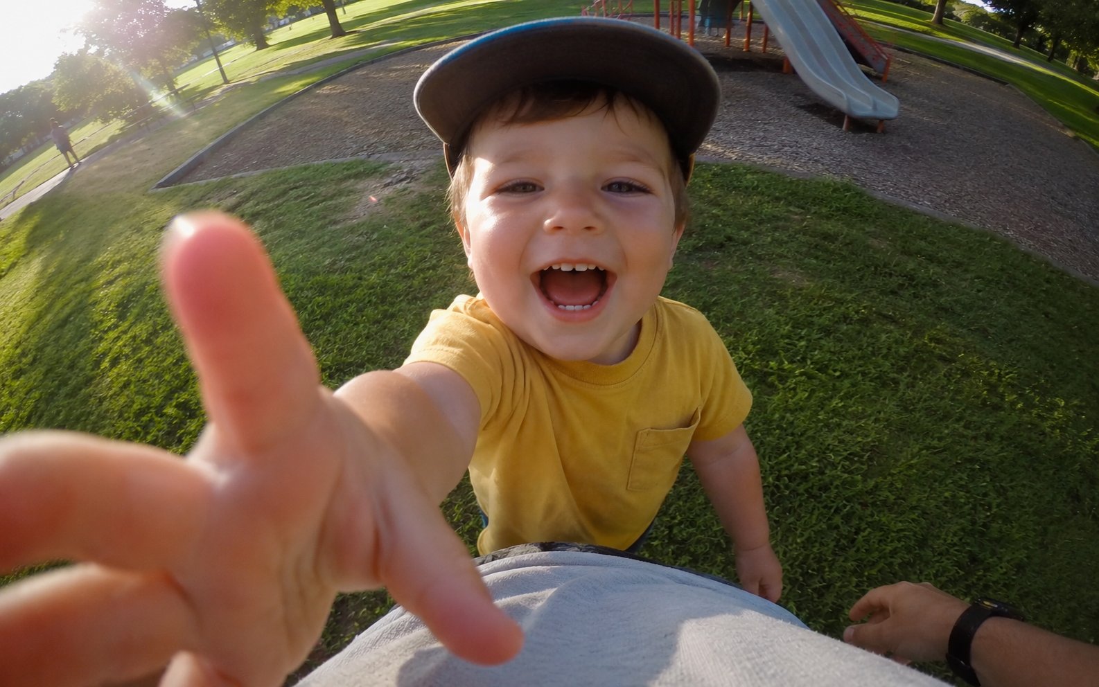 POV frame of a toddler reaching toward the camera at the park